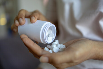 close up hands with pills out of the bottle 