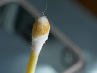 Earwax on a cotton swab, macro photo. Earwax, also known by the medical term cerumen, is a brown, orange, red, yellowish or gray waxy substance secreted in the ear canal of humans and other mammals.