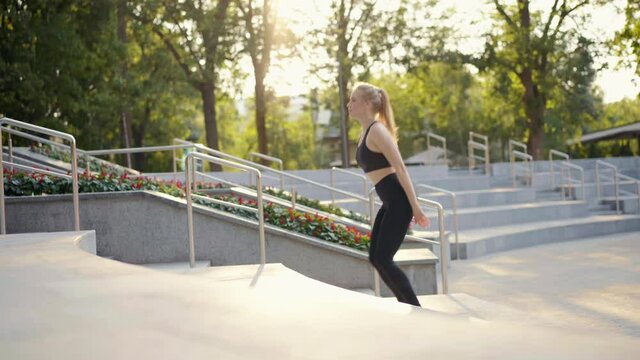 Young fit woman doing jump squats on stairs in park summer day Young Adult caucasian female practice jumping exercises outdoor Morning Workout training Cardio exercise Dressed black sportswear 