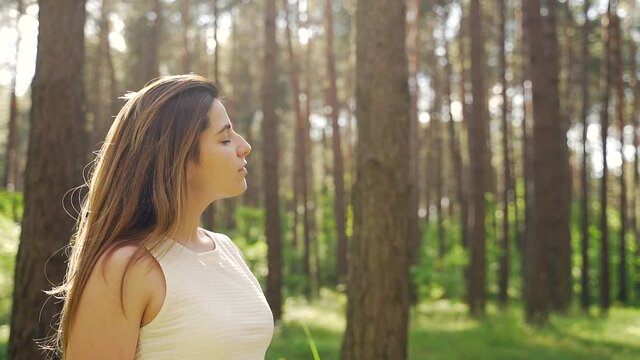 Close up portrait of a pretty young woman breathes fresh air into her full chest in the middle of pine forest on nature. Outdoor. freshness, peace and quiet. Girl with closed eyes enjoys the sounds