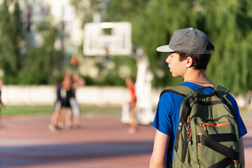 A teenage guy stands at the stadium and looks at basketball