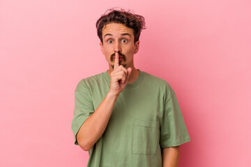 Young caucasian man isolated on pink background keeping a secret or asking for silence.