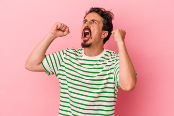 Fototapeta premium Young caucasian man isolated on pink background raising fist after a victory, winner concept.