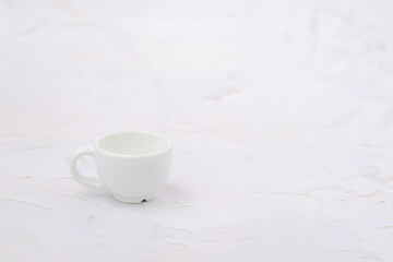 Obraz na płótnie Canvas White cup of coffee on the white rough background with copy space for drinks and beverage concept