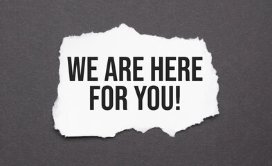 We are here for you sign on the torn paper on the black background