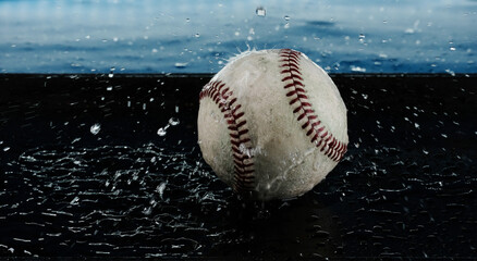Used baseball ball in water splash action for wet sports equipment or rain concept of game.
