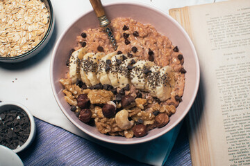 Bowl of oatmeal porridge with banana and nuts. Top view. Healthy vegan breakfast