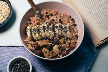 Bowl of oatmeal porridge with banana and nuts. Top view. Healthy vegan breakfast