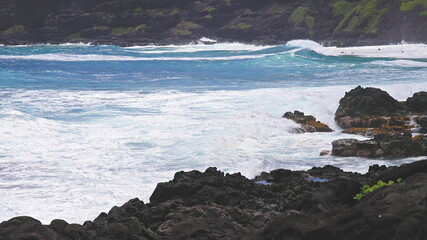 Blue Waves of the Pacific Ocean Beats Oahu Island Volcanic Cliffs. Turquoise water color. Clear sunny day. Archipelago Hawaii. DCI 4k. Slow Motion.