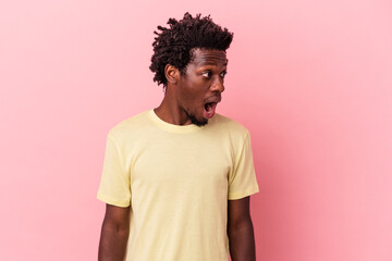 Young african american man isolated on pink background being shocked because of something she has seen.