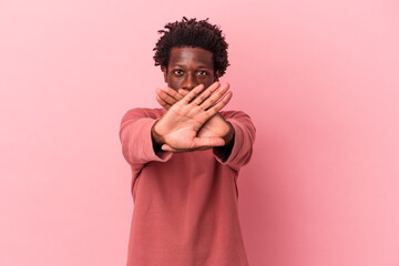 Young african american man isolated on pink background doing a denial gesture