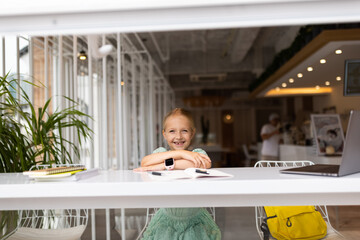 happy caucasian kid has online lesson on laptop during coronavirus covid-19 pandemic and lockdown