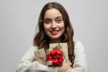 Fototapeta premium A young girl with long hair and a gift in her hands, smiling and looking straight at the camera
