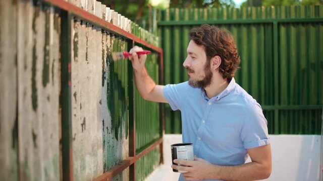 DIY Man paints an old metal fence wall into green
