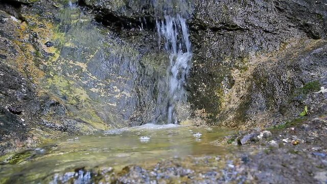 Small waterfall on large stone in Austrian Alps, klausbach river, valley near attersee