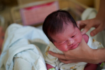 Newborn baby,her body is red sit in hospital crib,nurse hand holding baby neck in hospital.