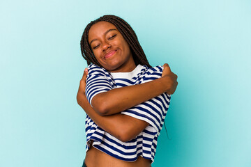 Young african american woman isolated on blue background  hugs, smiling carefree and happy.