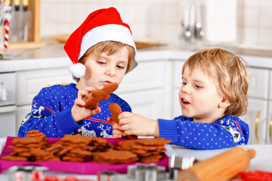 Two Little Preschool Boys Baking Gingerbread Cookies. Happy Siblings, Children In Xmas Sweaters. Kitchen Decorated For Christmas. Brothers Fighting, Making Trouble Chaos. Christmas Family Activity