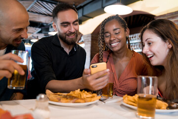 Group of friends using a mobile phone at a restaurant.