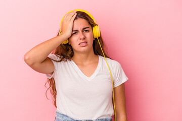Young caucasian woman listening to music isolated on pink background  being shocked, she has...