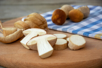 Sliced porcini mushrooms on a cutting board. Edible mushrooms on a checkered towel.