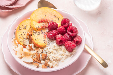 Porridge oatmeal with raspberries, peaches and nuts for breakfast. Healthy vegetarian food concept.