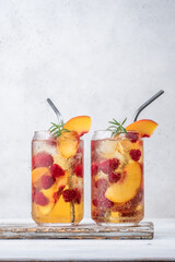 Delicious peach lemonade with soda water and raspberries. Fresh summer ice tea cocktail