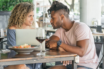 Couple using a laptop while having lunch together.