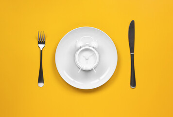 alarm clock on a dish with fork and knife	