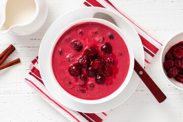 Sour cherry soup in a white bowl on a white background. Top view. Hungarian cold cherry soup with cream or sour cream, sugar and cinnamon. Sweet summer soup.