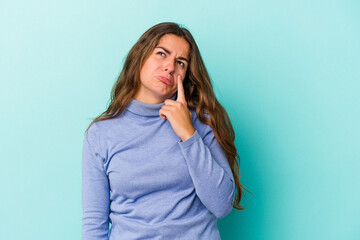 Young caucasian woman isolated on blue background  crying, unhappy with something, agony and confusion concept.