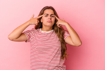 Young caucasian woman isolated on pink background  focused on a task, keeping forefingers pointing head.