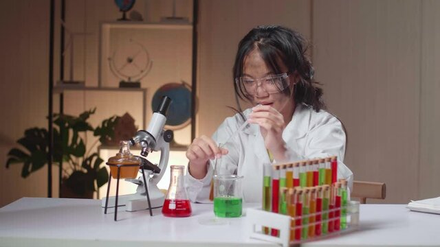 Excited Young Asian Scientist Girl With Dirty Face Mixes Chemicals In Test Tube. Child Learn With Interest
