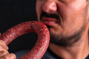 The man sniffs a circle of sausage and winces at the unpleasant smell