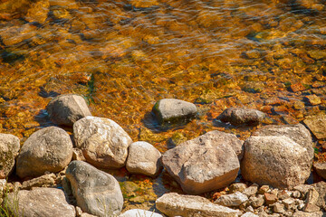 Small stones on the bank of the river with clear water.