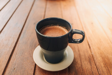 Blue mug of hot chocolate on dark wooden table in a cafe.