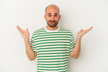 Young bald man isolated on white background confused and doubtful shrugging shoulders to hold a copy space.