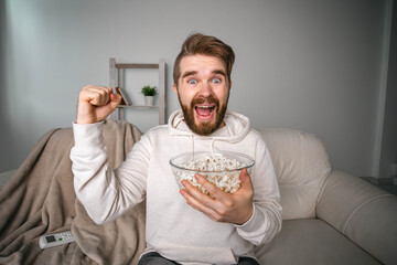 Emotional bearded man watching sport channels on Tv, supporting team at home. Sports fan and championship concept.