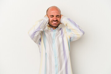 Young bald man isolated on white background covering ears with hands.