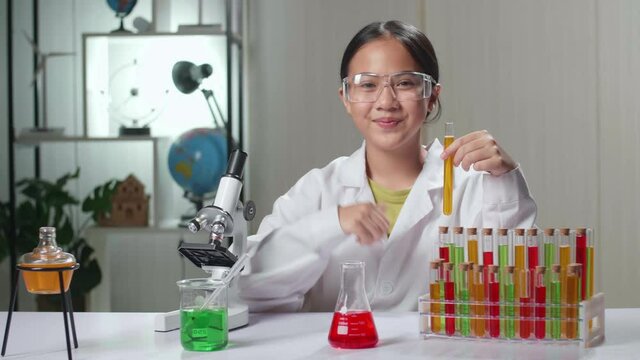 Young Asian Scientist Girl Looking At Liquid In Test Tube And Showing Thumb Up
