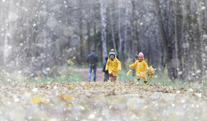 Toddlers on a walk in the autumn park. First frost and the first snow in the autumn forest. Children play in the park with snow and leaves.