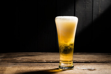 Beer glass with white beer foam on wooden floor dark wood background