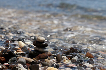 Pebble stones on blurred background of sea waves. Summer vacation, stone tower, balance and relax concept