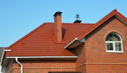 A red metal roofing construction of a red brick house with roof gutters, downpipe, soffit, fascia...