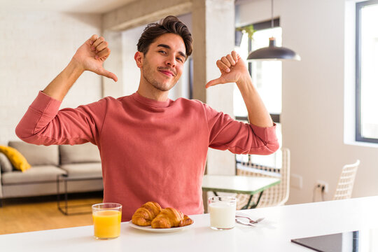 Young mixed race man having breakfast in a kitchen on the morning feels proud and self confident, example to follow.