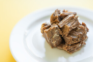 Canned beef stew on white plate with parsley leaf, yellow background