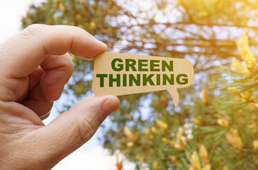 A man holds a sign inside which the inscription - Green Thinking