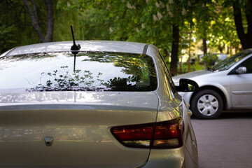 Back window of grey car parked on the street in summer sunny day, rear view. Mock-up for sticker or...