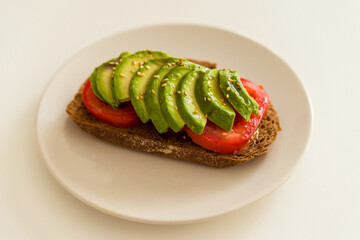 Toast with avocato, tomato and cereals bread on a dish