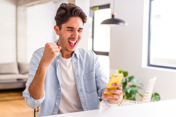 Young mixed race man talking on the phone in a kitchen